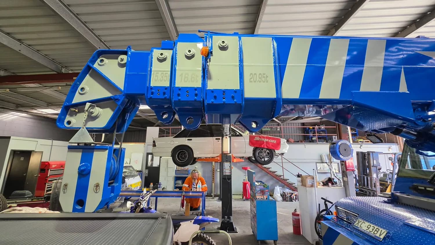 Blue mobile crane mid-wrap in workshop