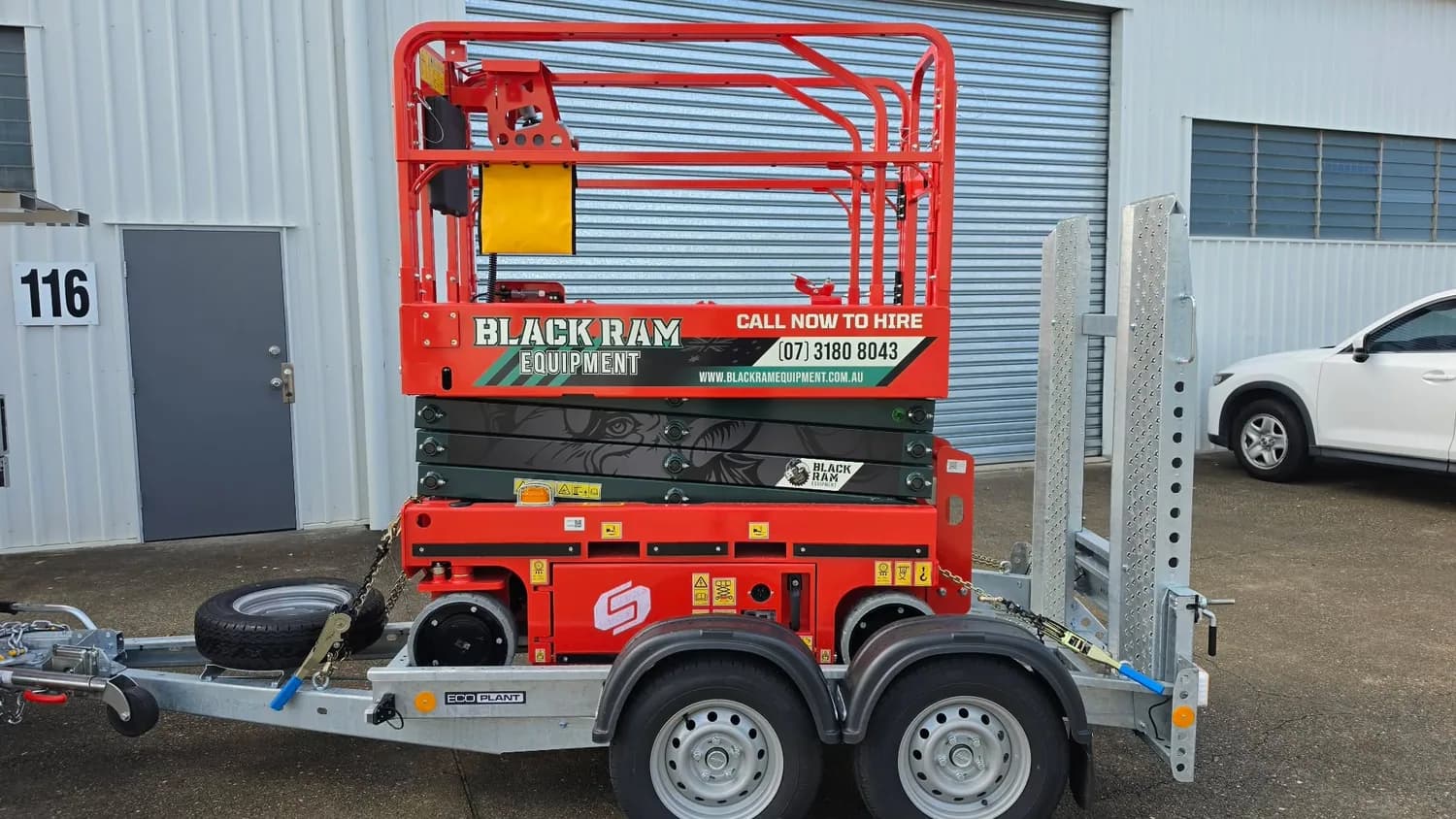 Black Ram Equipment red scissor lift on trailer, wrapped