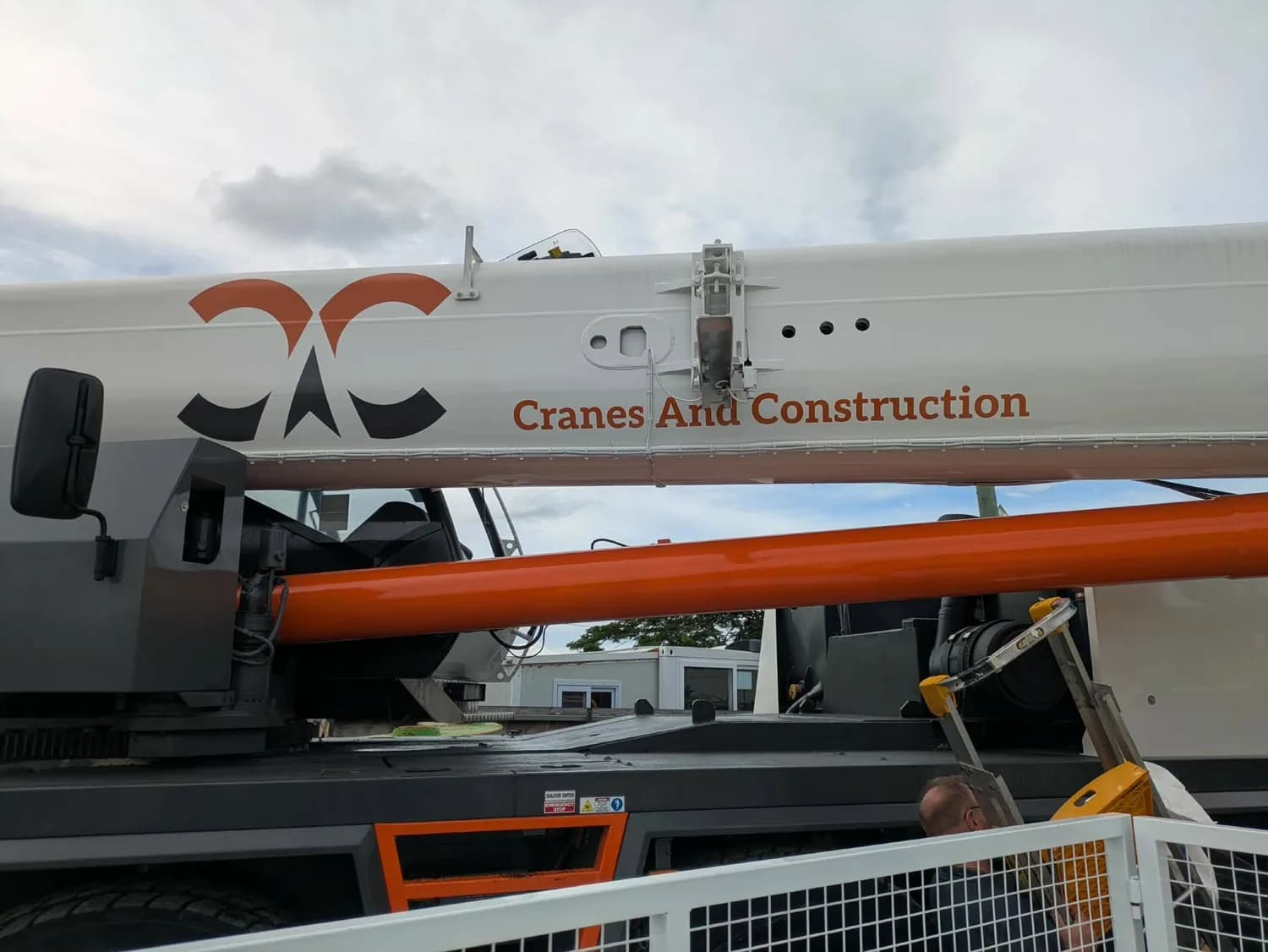 Cranes And Construction crane truck with orange boom and branding