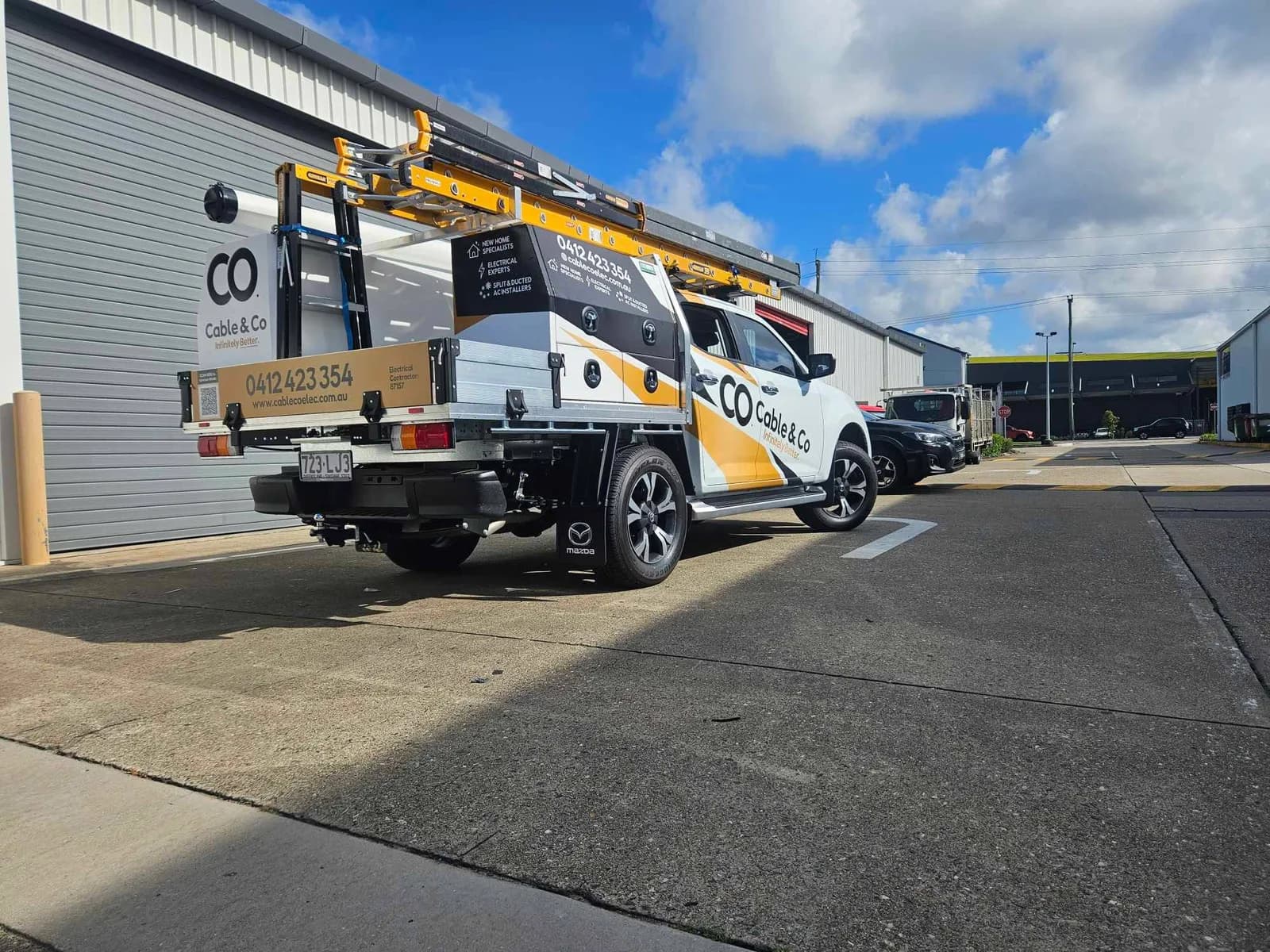Cable & Co single cab tray with elevated work platform, matching building signage behind