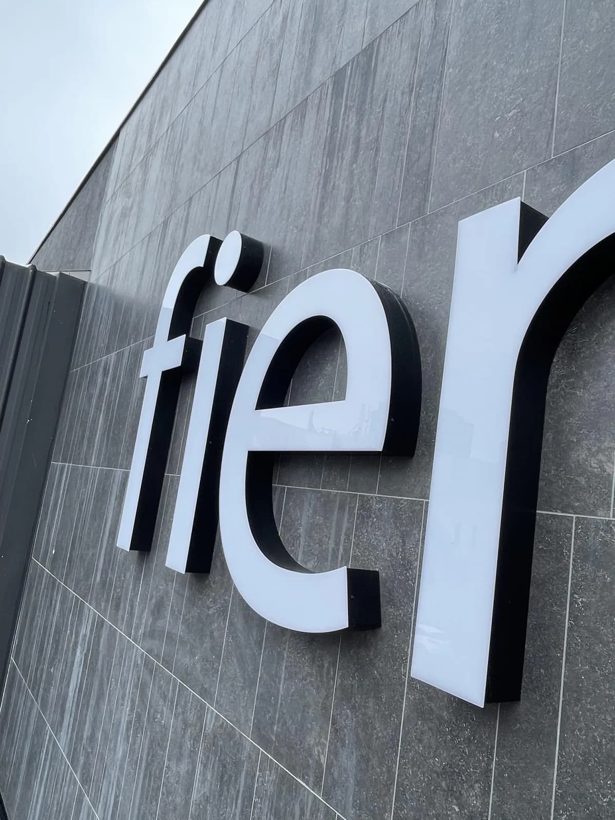 Illuminated Fienza letters close up on a dark tiled fascia