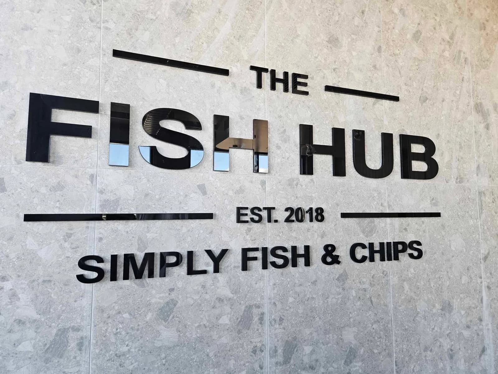 The Fish Hub 3D letters on a stone-tiled wall