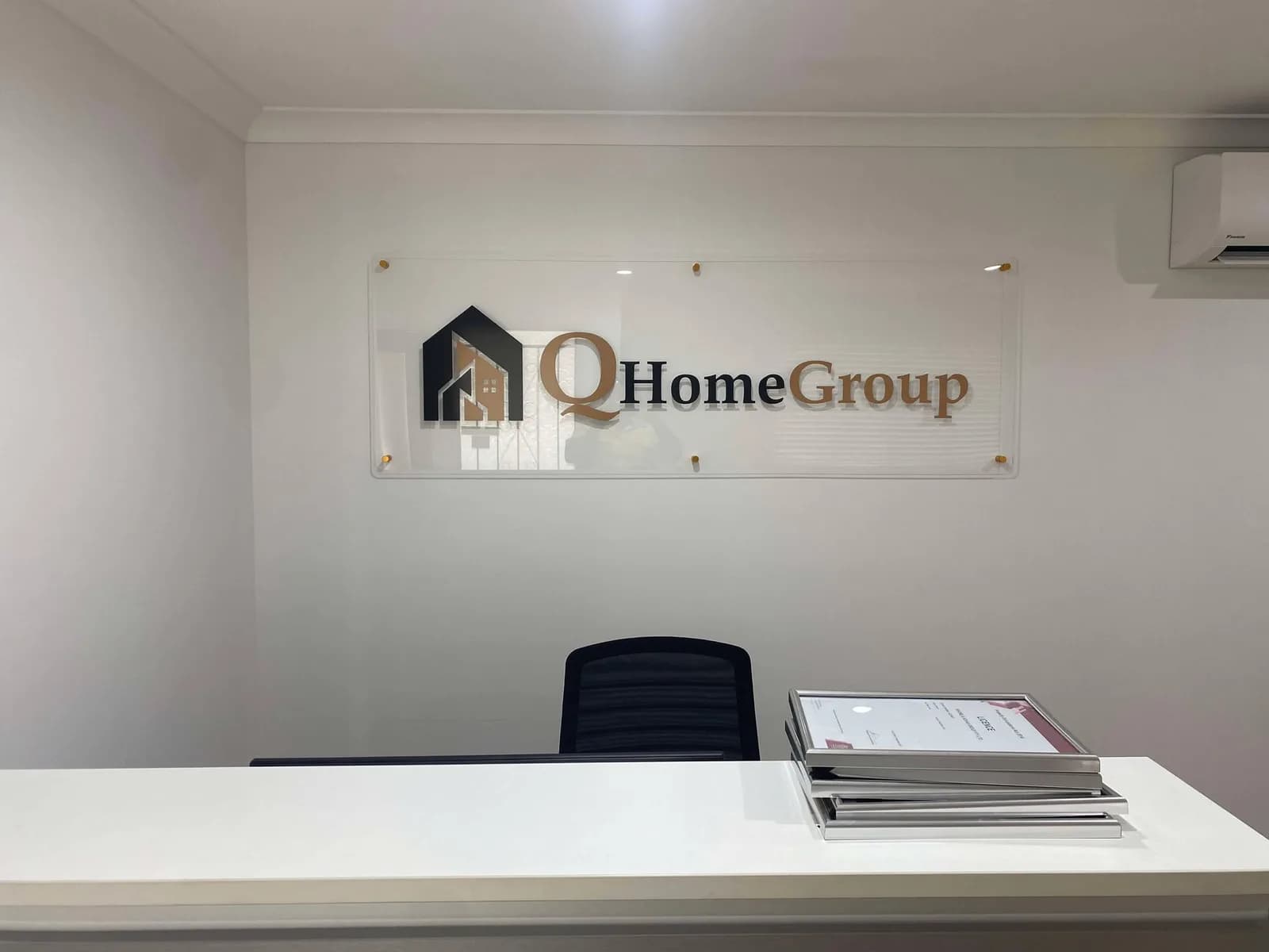 Q Home Group acrylic standoff sign above a reception desk
