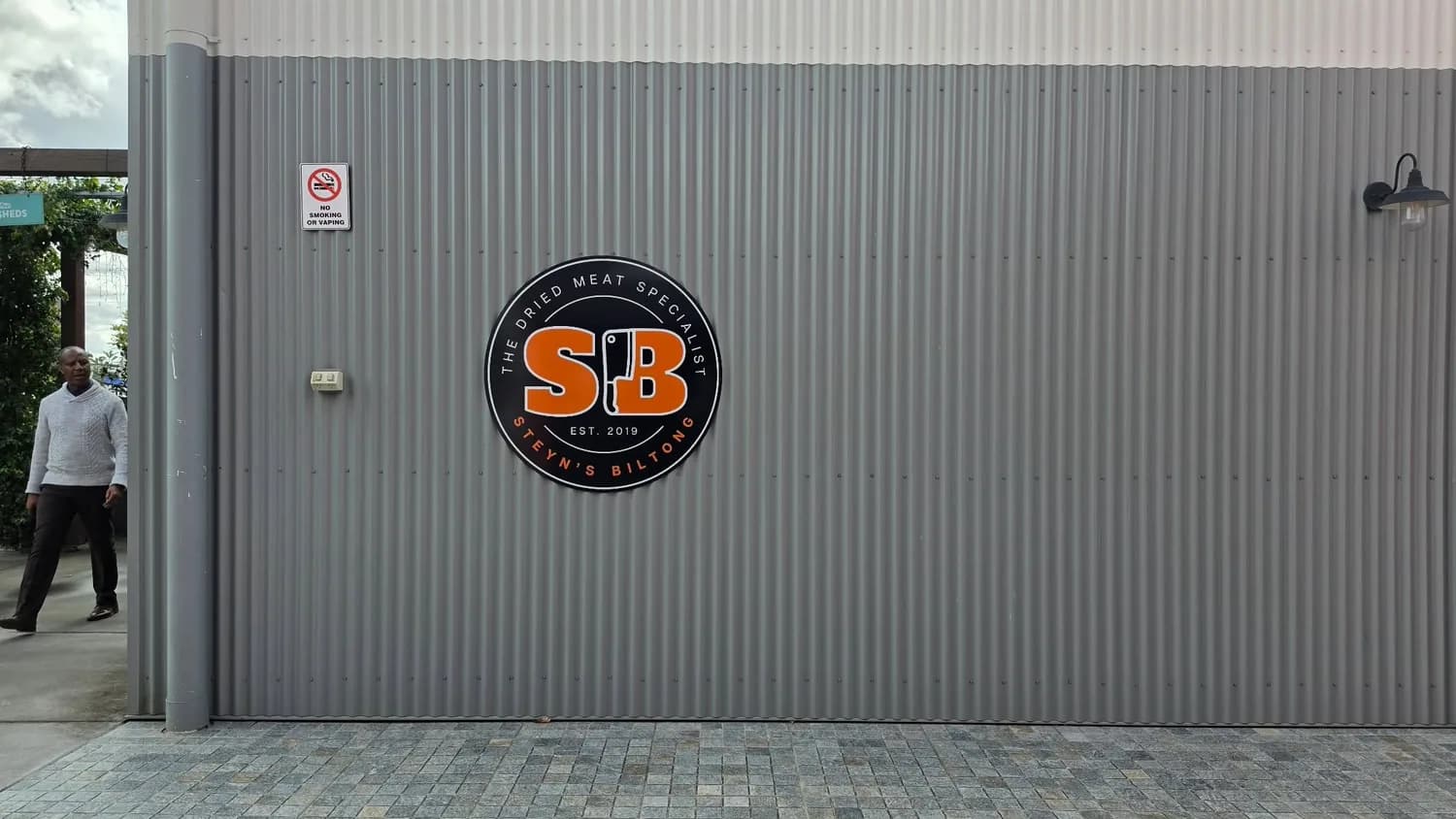 SB circular logo panel on grey corrugated exterior wall